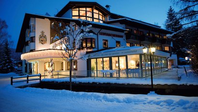 Beleuchtetes Hotelgebäude im Schnee bei Abenddämmerung
