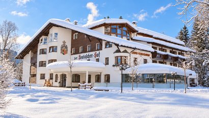Das verschneite Hotel Der Leutascher-Hof vor blauem Winterhimmel