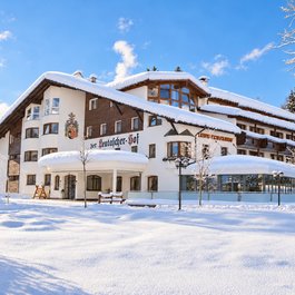 Das verschneite Hotel Der Leutascher-Hof vor blauem Winterhimmel
